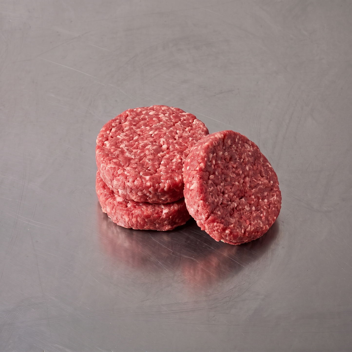 Grass Fed Burger Patties ~500g on stainless steel butcher's bench